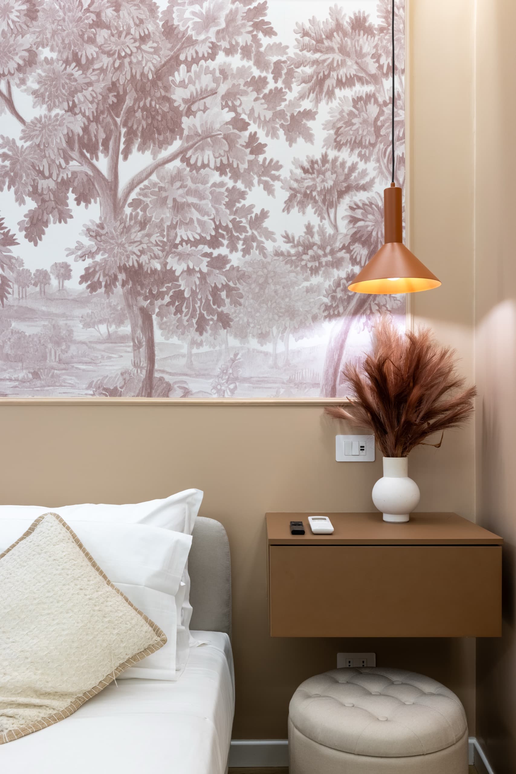 Dettaglio di camera da letto con carta da parati toile, lampada a sospensione in rame e biancheria immacolata — suite Milizie, Roma