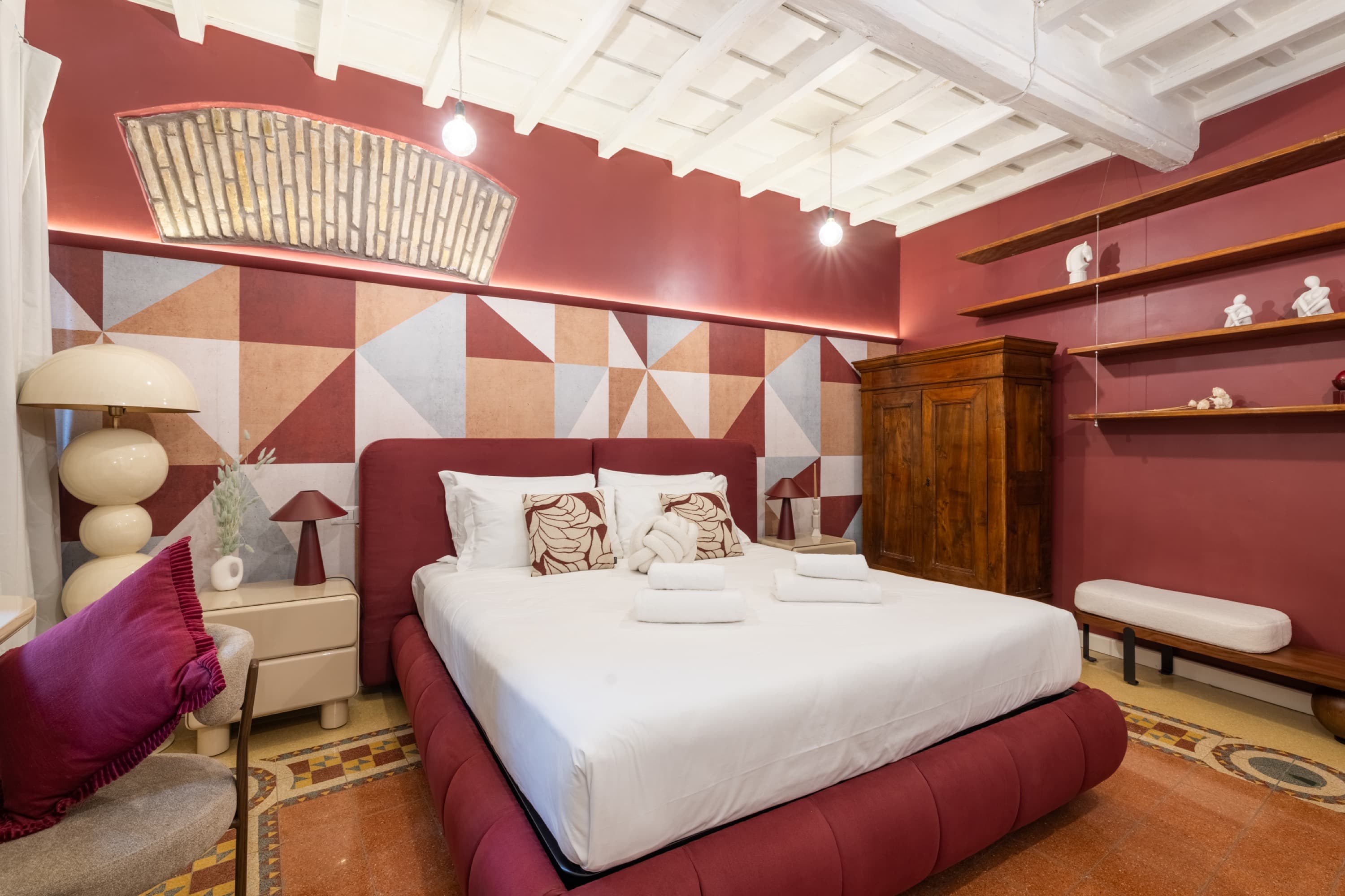 Camera da letto con arco in mattoni a vista retroilluminato e biancheria immacolata — appartamento Via Minerva, Roma